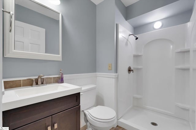 bathroom with vanity, toilet, and a shower