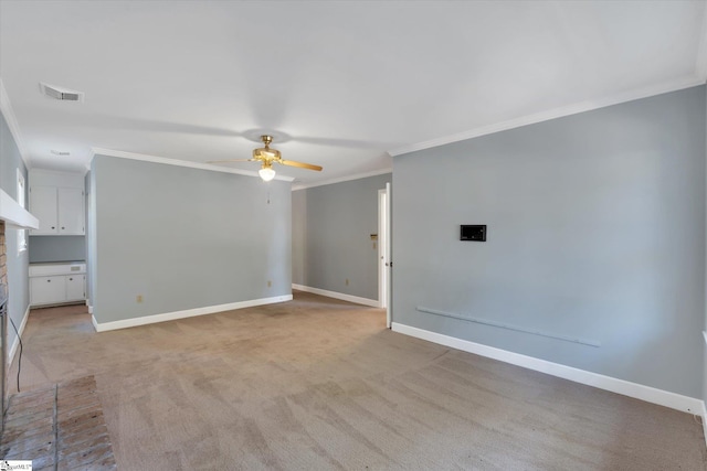 spare room with ceiling fan, light colored carpet, crown molding, and a brick fireplace