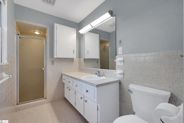 bathroom featuring vanity, a shower with shower door, tile walls, and toilet