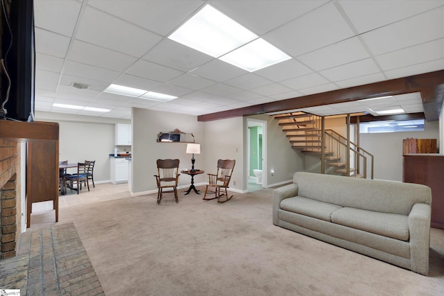 carpeted living room featuring a fireplace and a drop ceiling