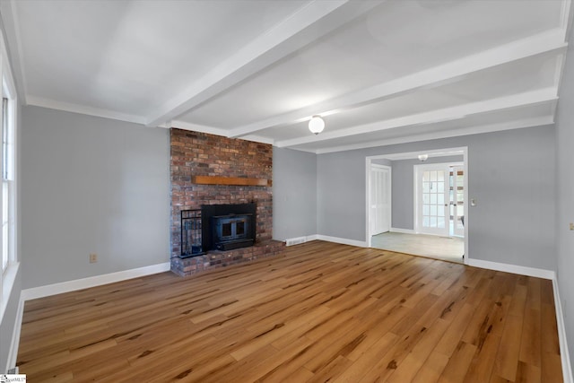 unfurnished living room with beam ceiling, a wood stove, and hardwood / wood-style floors