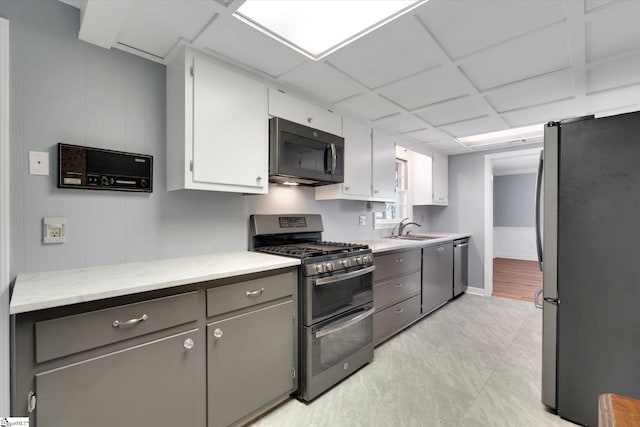 kitchen featuring white cabinets, stainless steel appliances, gray cabinets, and sink