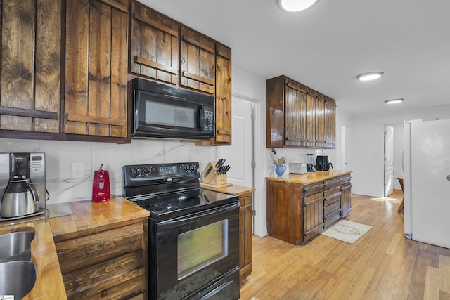 kitchen featuring black appliances, dark brown cabinets, tasteful backsplash, and light hardwood / wood-style flooring