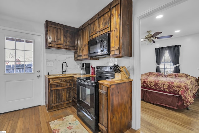 kitchen with light wood-type flooring, dark brown cabinetry, ceiling fan, sink, and black appliances