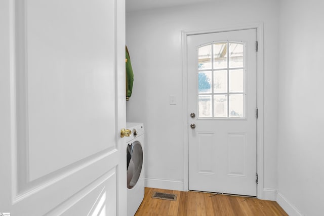 washroom with washing machine and clothes dryer and light hardwood / wood-style flooring