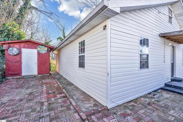 view of side of property with a storage unit and a patio area