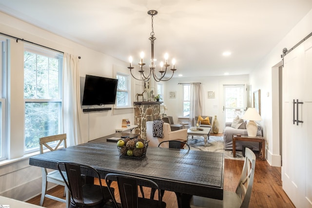 dining space with a barn door, hardwood / wood-style flooring, and an inviting chandelier