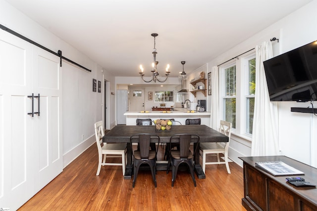 dining room featuring a barn door, wood-type flooring, and a chandelier