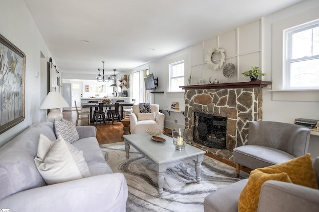 living room featuring a stone fireplace, a healthy amount of sunlight, and wood-type flooring