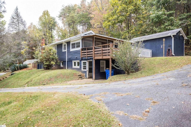 view of front of house featuring a sunroom, a deck, and a front yard