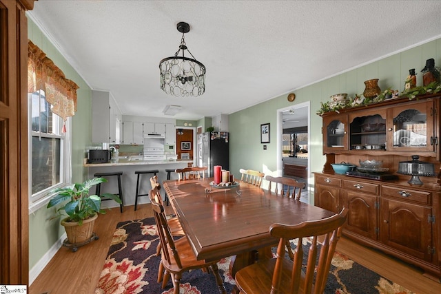 dining area with a chandelier, a textured ceiling, and light hardwood / wood-style flooring