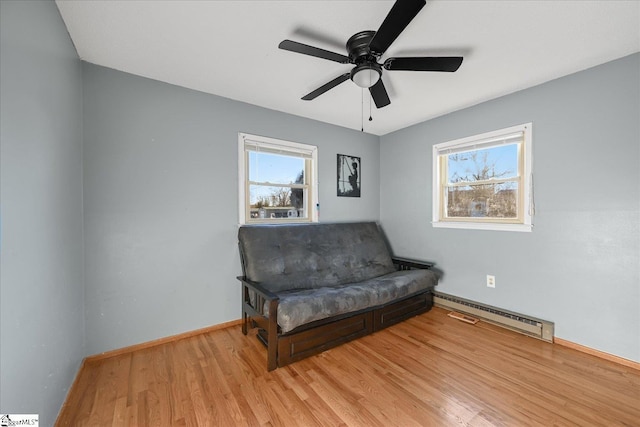 sitting room featuring light hardwood / wood-style floors, a wealth of natural light, a baseboard heating unit, and ceiling fan