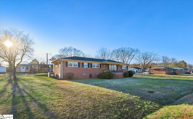 ranch-style house with a front yard and central AC unit