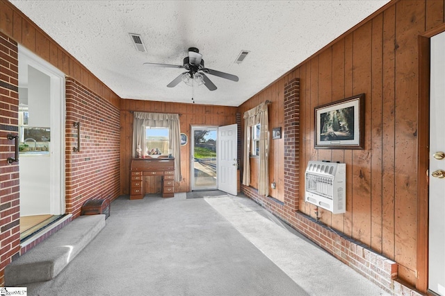 unfurnished sunroom featuring ceiling fan and heating unit