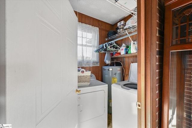 laundry area with washing machine and dryer, electric water heater, and wooden walls