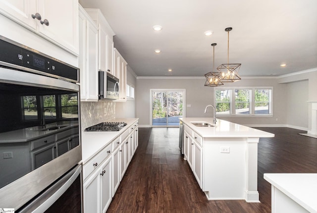 kitchen with an inviting chandelier, a center island with sink, sink, white cabinetry, and stainless steel appliances