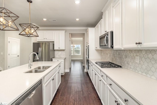 kitchen featuring sink, stainless steel appliances, dark wood-type flooring, pendant lighting, and white cabinets