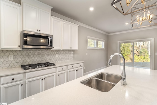 kitchen featuring appliances with stainless steel finishes, white cabinetry, pendant lighting, and sink