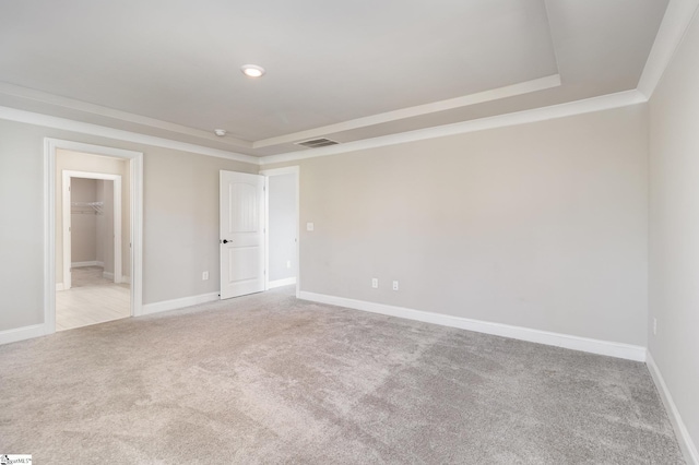 carpeted empty room featuring a raised ceiling and ornamental molding