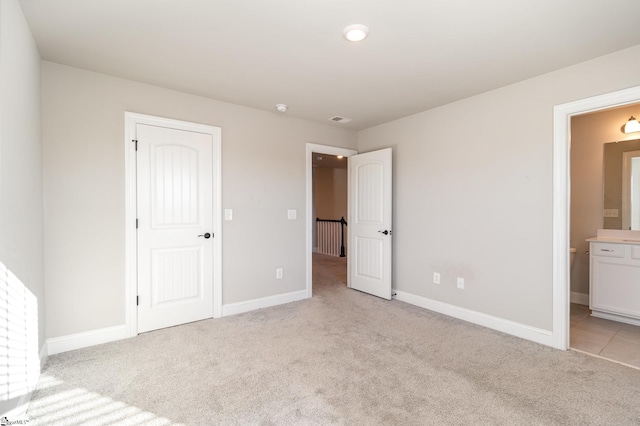 unfurnished bedroom featuring connected bathroom and light carpet