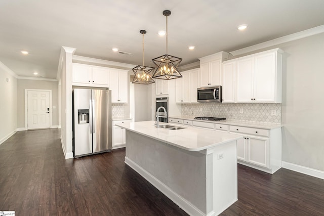 kitchen with pendant lighting, white cabinets, stainless steel appliances, and an island with sink