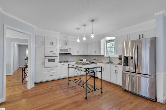 kitchen with white cabinetry, sink, decorative light fixtures, white appliances, and light wood-type flooring