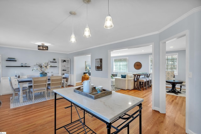 kitchen featuring plenty of natural light, light wood-type flooring, crown molding, and decorative light fixtures