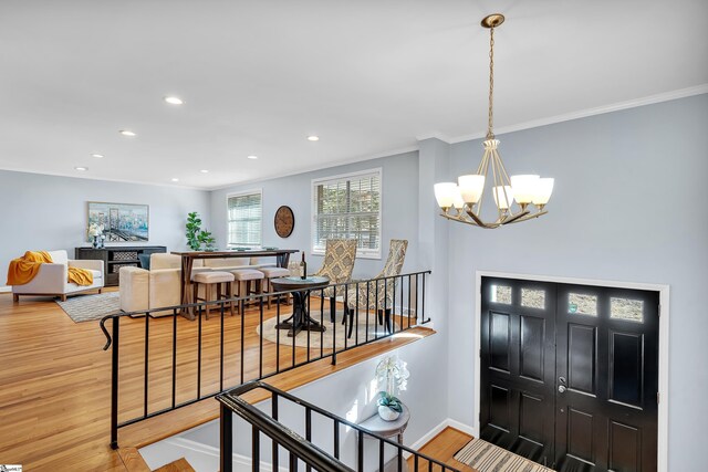 entrance foyer with a chandelier, wood-type flooring, and crown molding