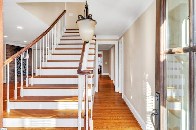 stairs with hardwood / wood-style flooring and ornamental molding