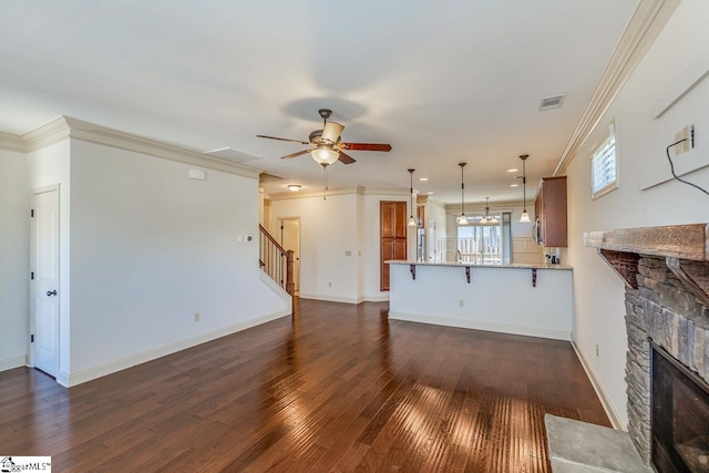 unfurnished living room with dark hardwood / wood-style flooring, ceiling fan, a fireplace, and crown molding