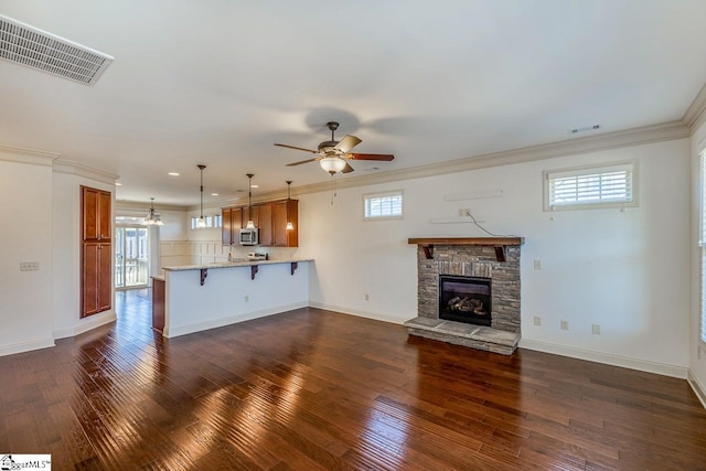 unfurnished living room with ceiling fan, a fireplace, a healthy amount of sunlight, and dark wood-type flooring