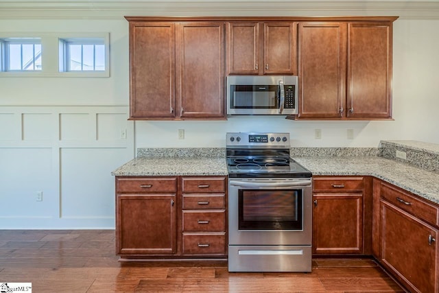 kitchen featuring light stone counters, dark wood-type flooring, stainless steel appliances, and ornamental molding