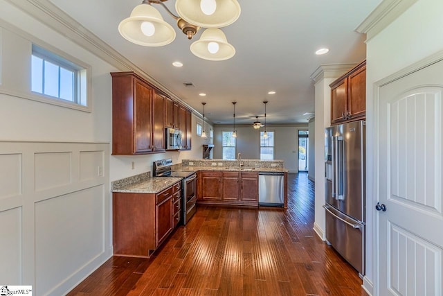 kitchen featuring sink, stainless steel appliances, kitchen peninsula, pendant lighting, and ornamental molding