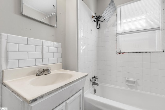 bathroom featuring tiled shower / bath combo, vanity, and tasteful backsplash