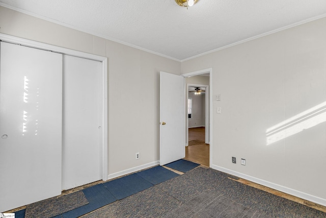 unfurnished bedroom featuring a textured ceiling, a closet, and crown molding