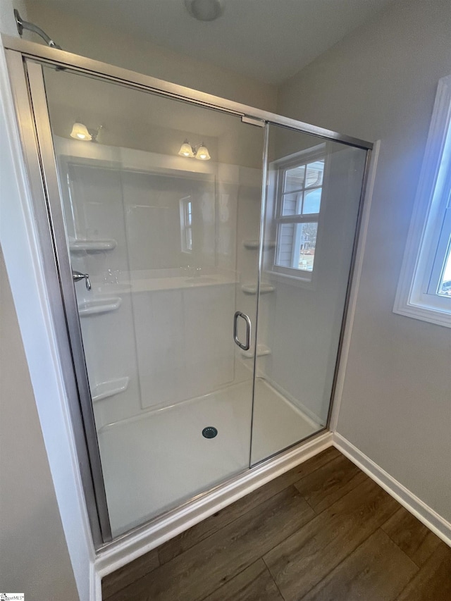 bathroom with plenty of natural light, a shower with shower door, and wood-type flooring