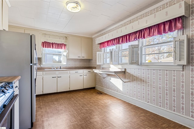 kitchen with stainless steel appliances, parquet floors, ornamental molding, and sink