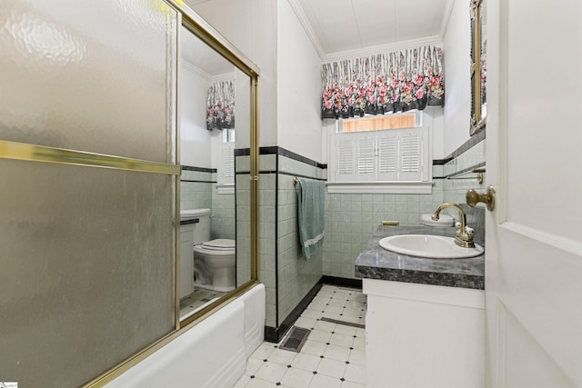 full bathroom with combined bath / shower with glass door, crown molding, toilet, vanity, and tile walls