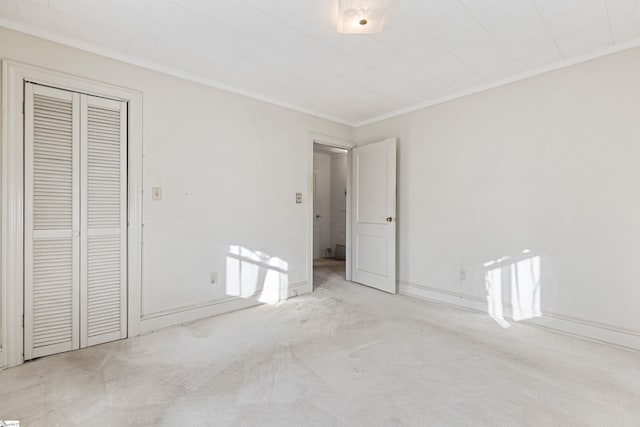 unfurnished bedroom featuring light colored carpet, ornamental molding, and a closet