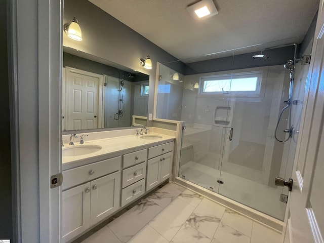 bathroom with a shower with door, vanity, and a textured ceiling