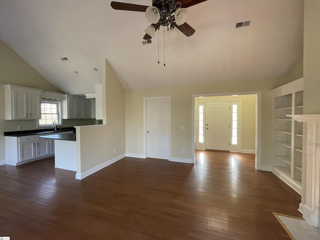 interior space with built in shelves, ceiling fan, dark hardwood / wood-style flooring, lofted ceiling, and white cabinets