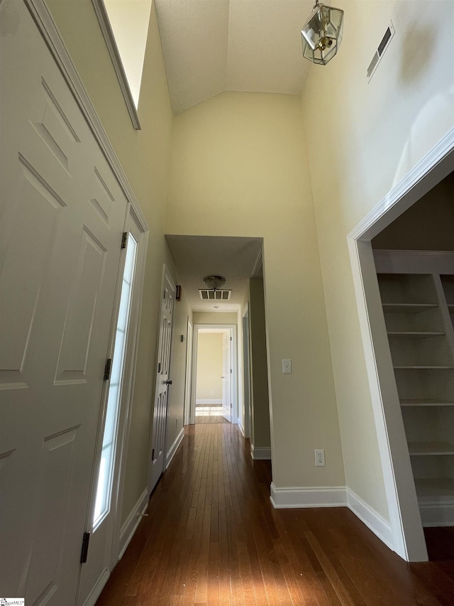 hallway featuring dark hardwood / wood-style flooring and vaulted ceiling