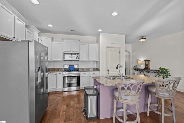 kitchen featuring stainless steel appliances, white cabinetry, a center island with sink, and sink