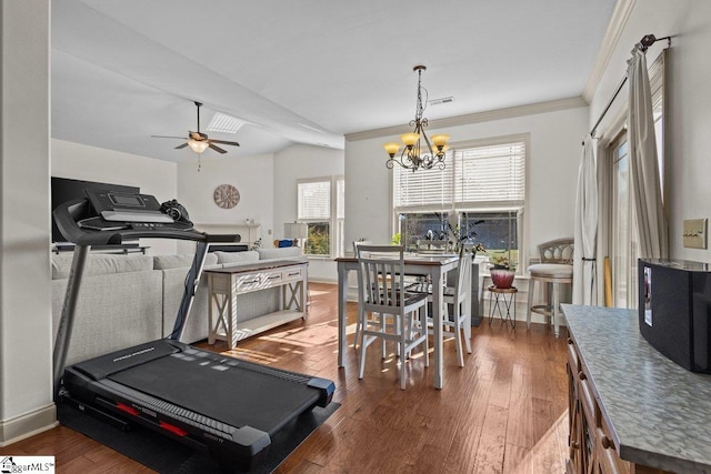 exercise room featuring ceiling fan with notable chandelier, dark hardwood / wood-style flooring, lofted ceiling, and crown molding