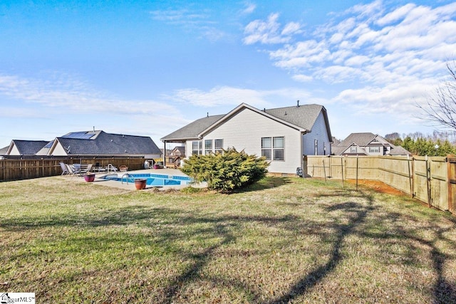 back of house featuring a lawn and a fenced in pool