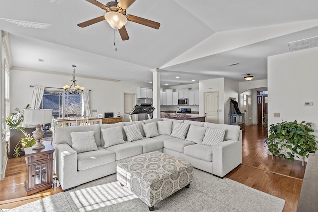 living room with vaulted ceiling, hardwood / wood-style floors, and ceiling fan with notable chandelier