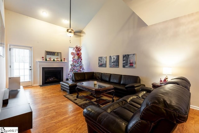 living room featuring ceiling fan, high vaulted ceiling, and light hardwood / wood-style floors