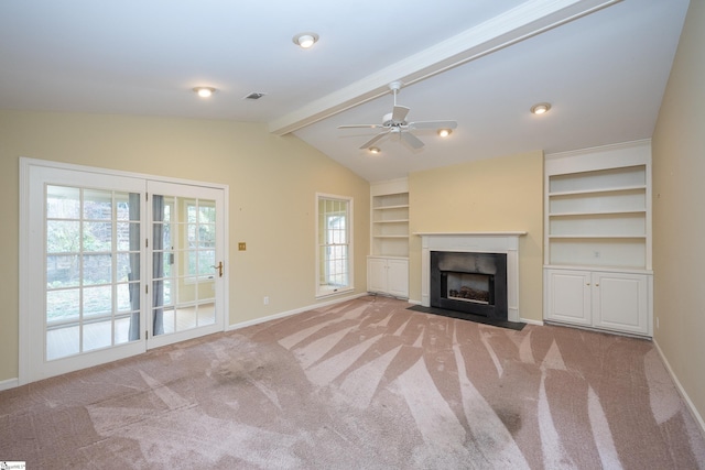 unfurnished living room featuring vaulted ceiling with beams, ceiling fan, light colored carpet, and a wealth of natural light