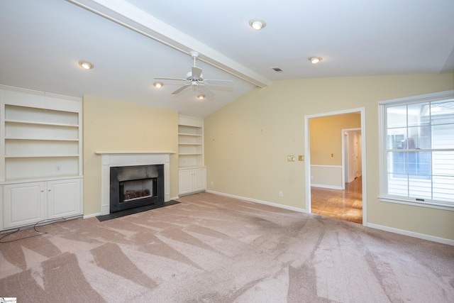 unfurnished living room with vaulted ceiling with beams, ceiling fan, light colored carpet, and built in features