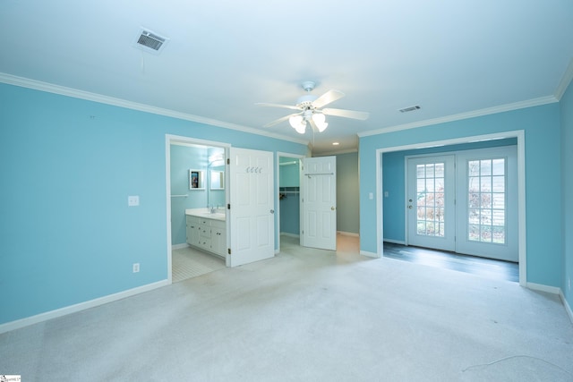 unfurnished bedroom with ensuite bathroom, ceiling fan, crown molding, and light colored carpet